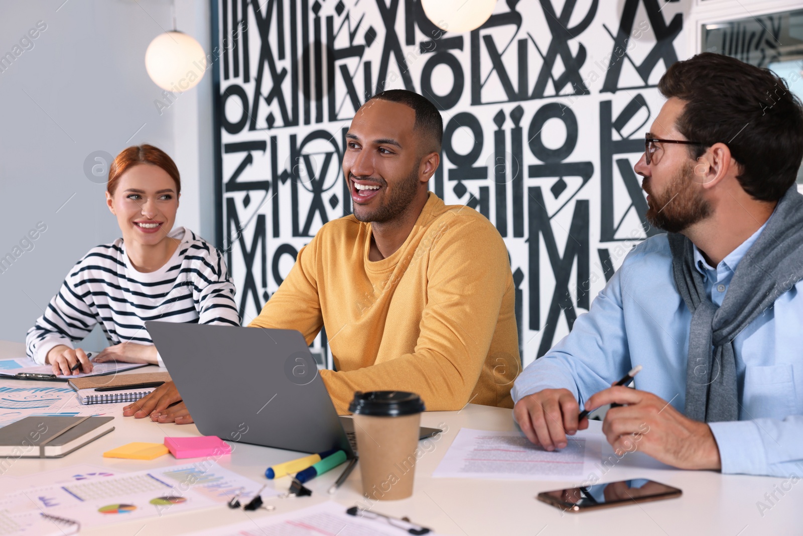 Photo of Team of employees working together at table in office. Startup project