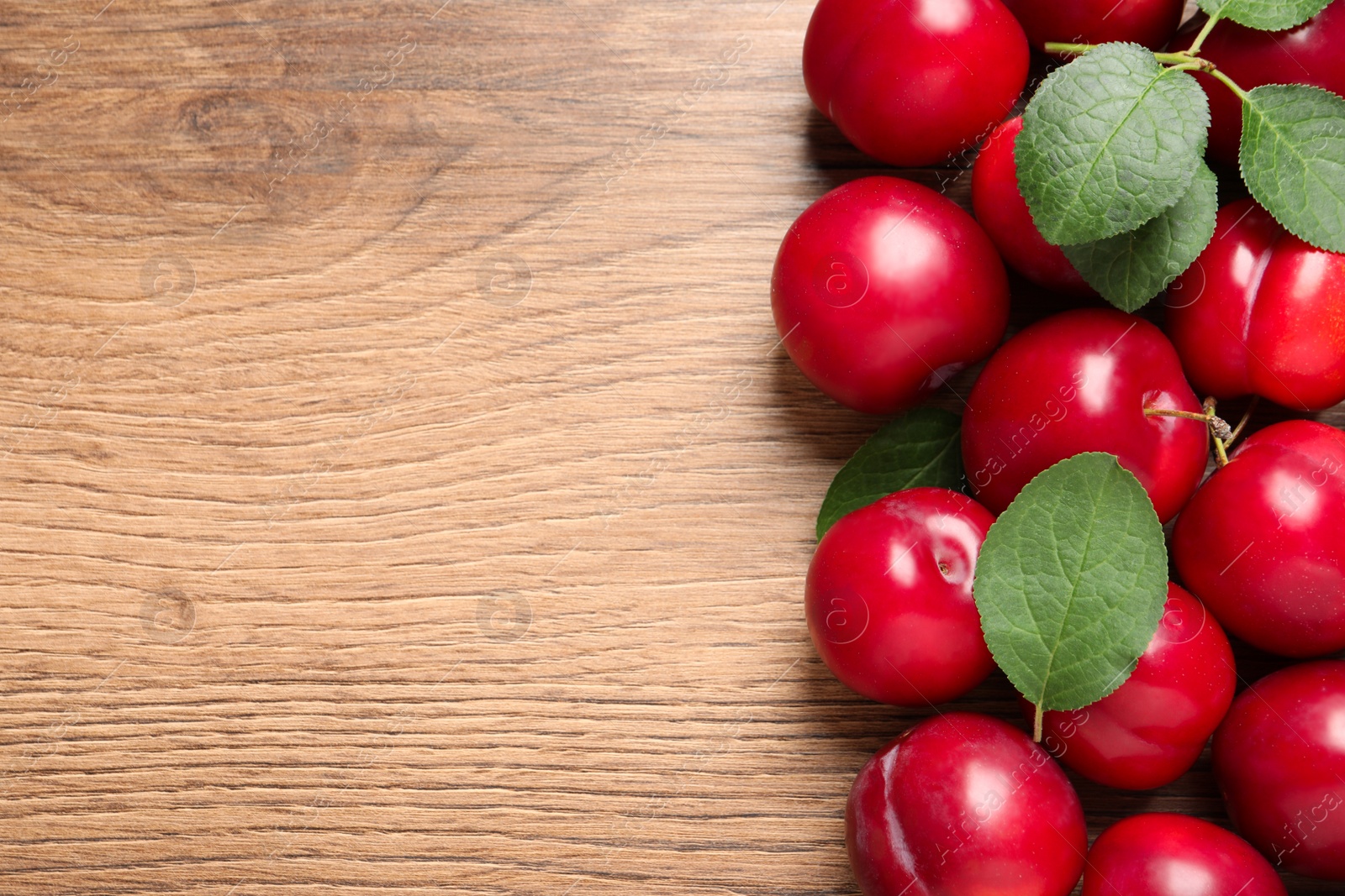 Photo of Fresh ripe cherry plums on wooden table, flat lay. Space for text