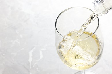 Photo of Pouring tasty aromatic wine in glass at gray marble table, closeup. Space for text