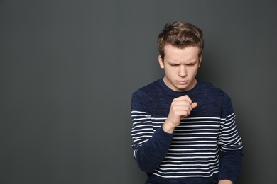 Photo of Teenage boy suffering from cough on dark background. Space for text