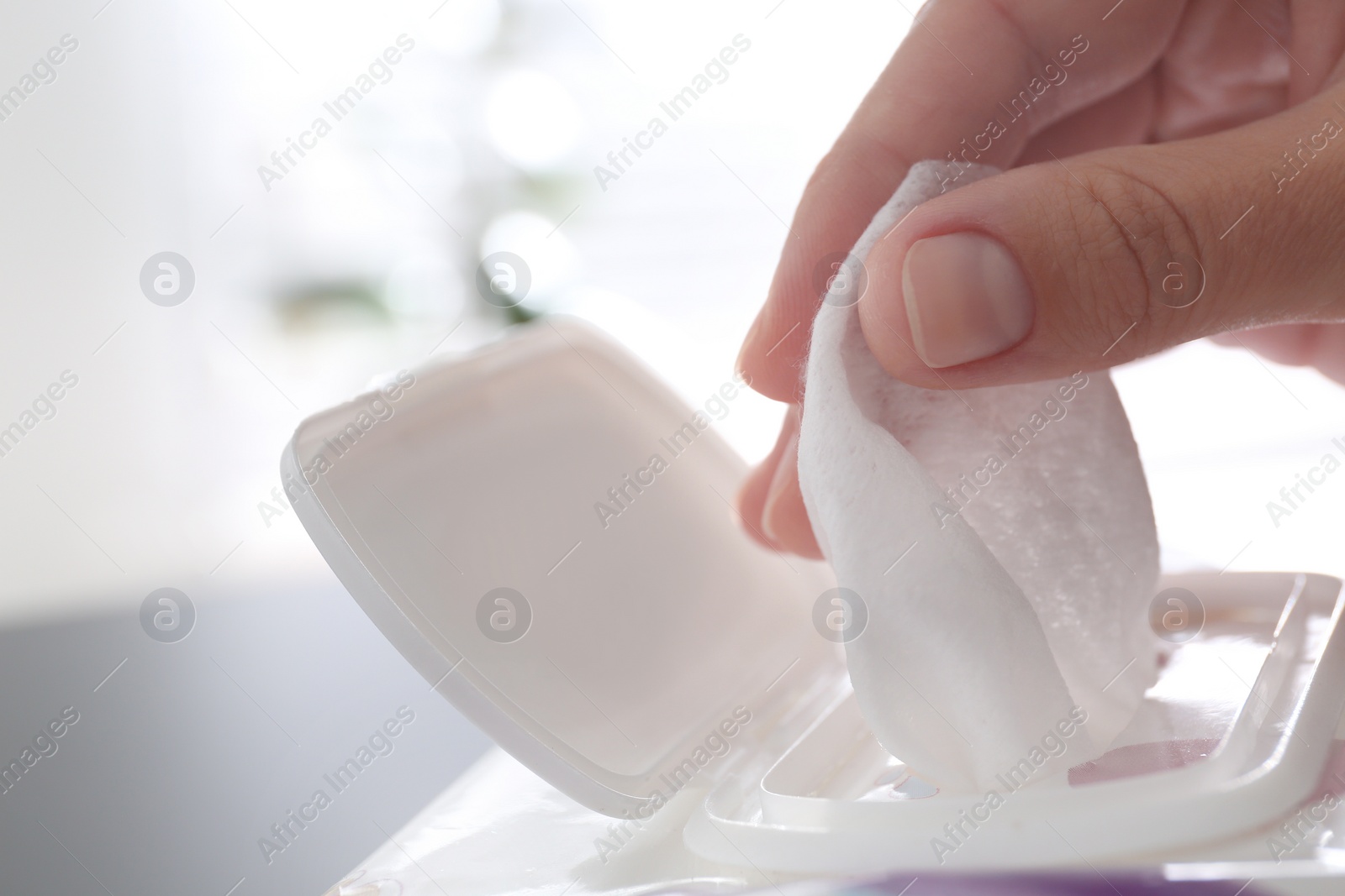 Photo of Woman taking wet wipe from pack on blurred background, closeup