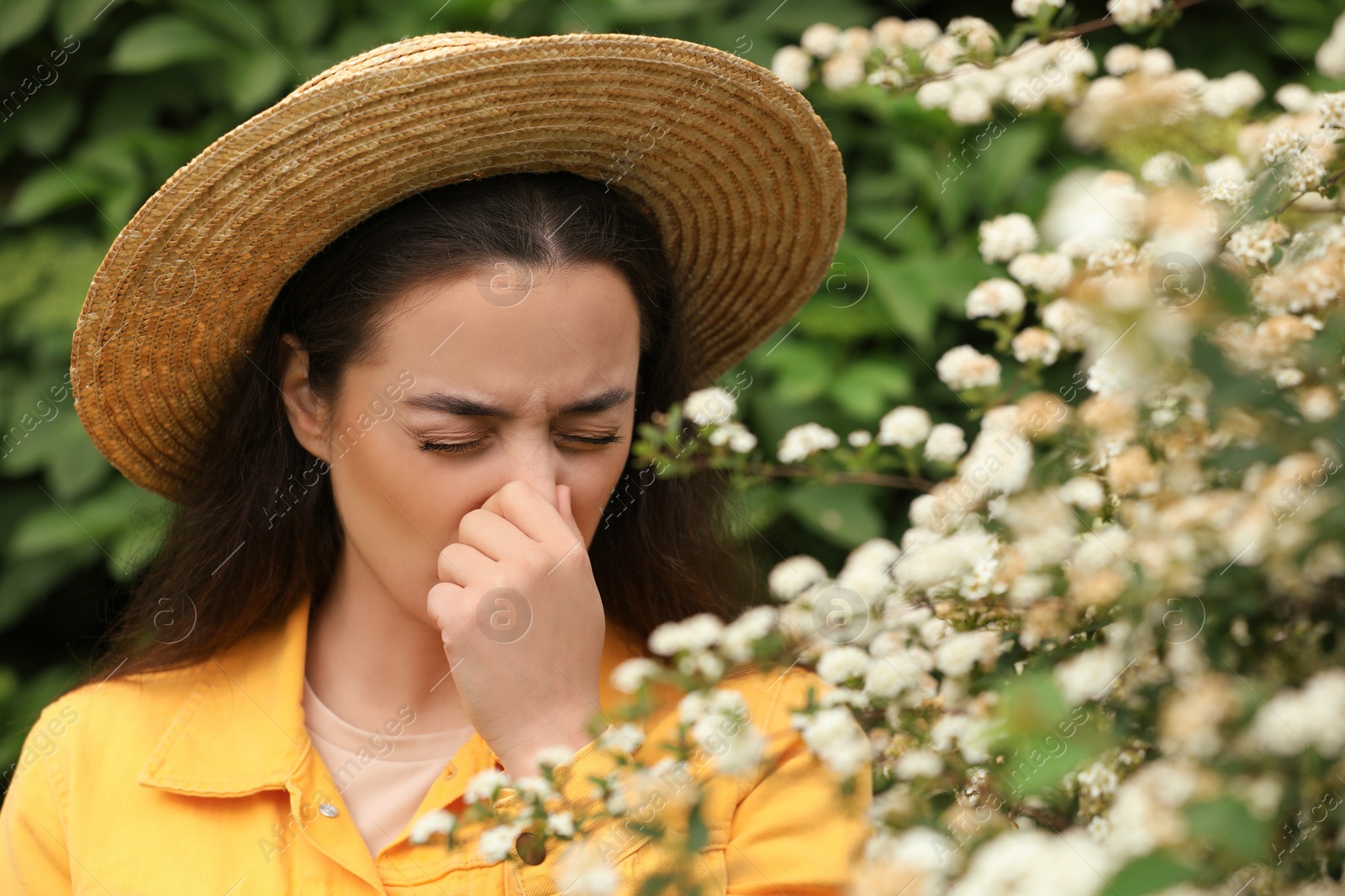 Photo of Woman suffering from seasonal pollen allergy near blossoming tree on spring day