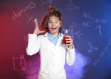 Emotional pupil holding conical flask in smoke against blackboard with chemistry formulas