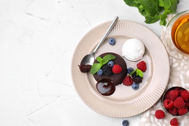 Photo of Delicious chocolate fondant served with fresh berries and ice cream on white table, flat lay. Space for text