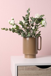 Photo of Stylish ceramic vase with beautiful flowers and eucalyptus branches on white table near pink wall