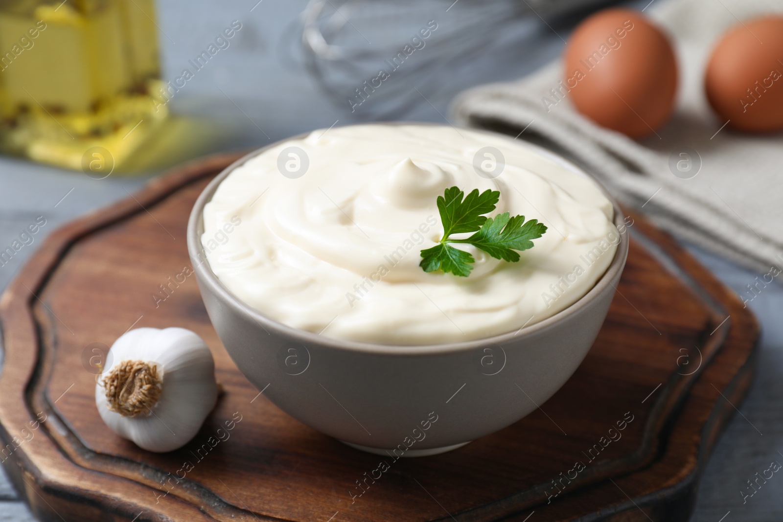 Photo of Tasty mayonnaise in bowl and garlic on table, closeup