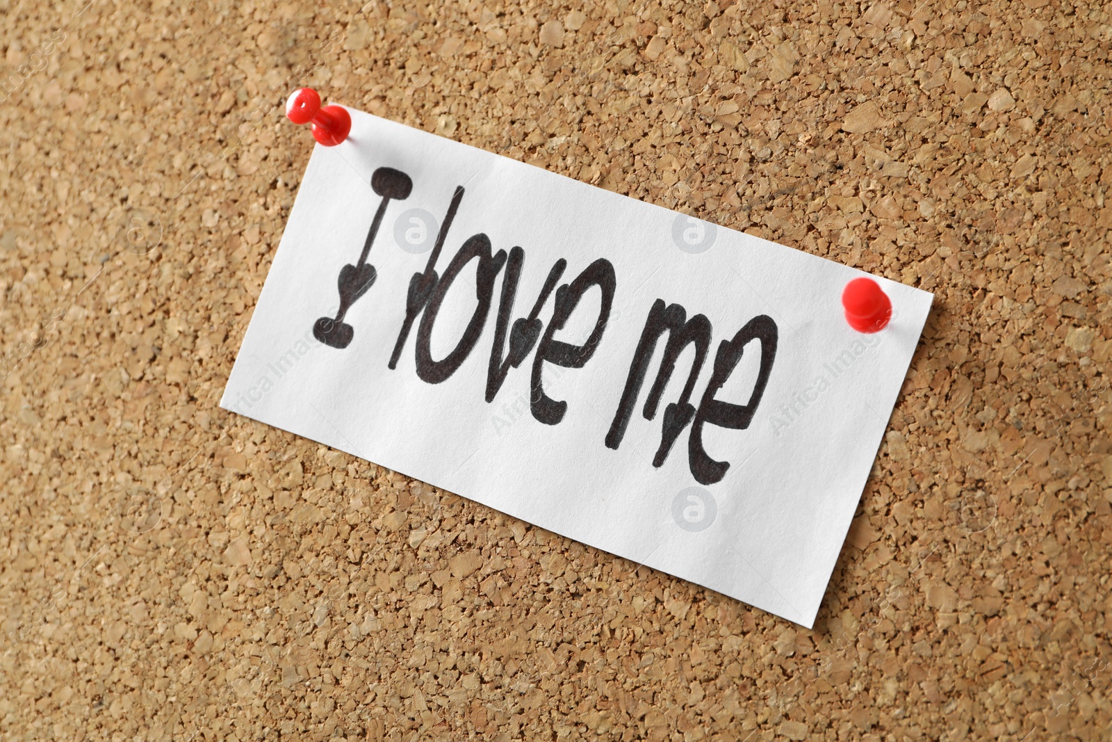 Photo of Paper with handwritten phrase I Love Me pinned on cork board, closeup