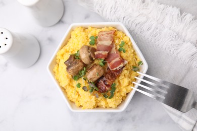 Photo of Cooked cornmeal with bacon, mushrooms and microgreens in bowl on white marble table, top view