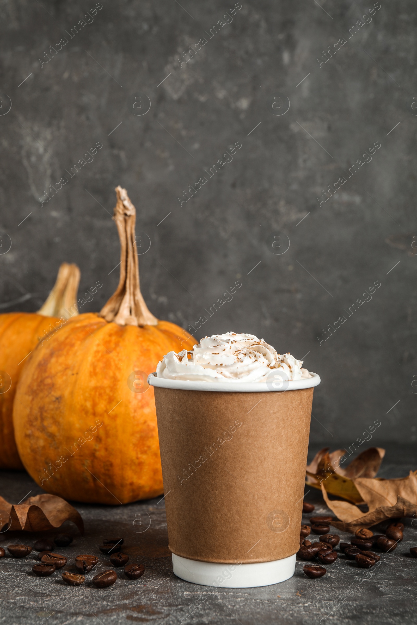 Photo of Paper cup with tasty pumpkin spice latte on grey table