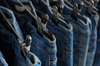 Metal hangers with different stylish jeans, closeup