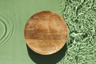 Photo of Presentation for product. Wooden podium in water on green background, top view