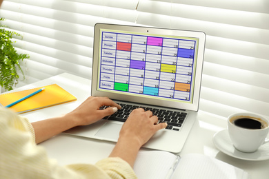 Photo of Young woman using calendar app on laptop in office, closeup