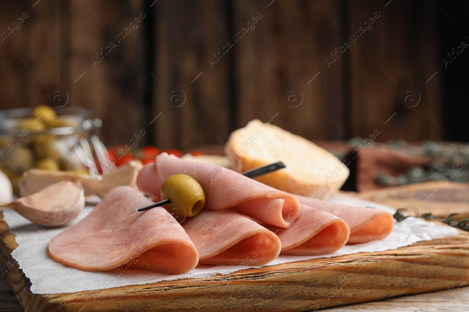 Photo of Slices of tasty ham with olive on table, closeup