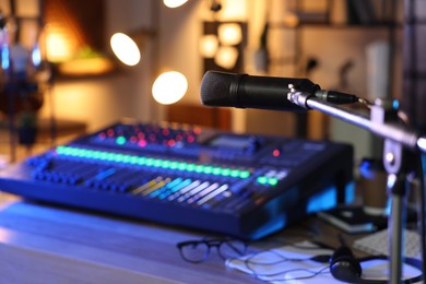 Photo of Microphone near table with professional mixing console in radio studio