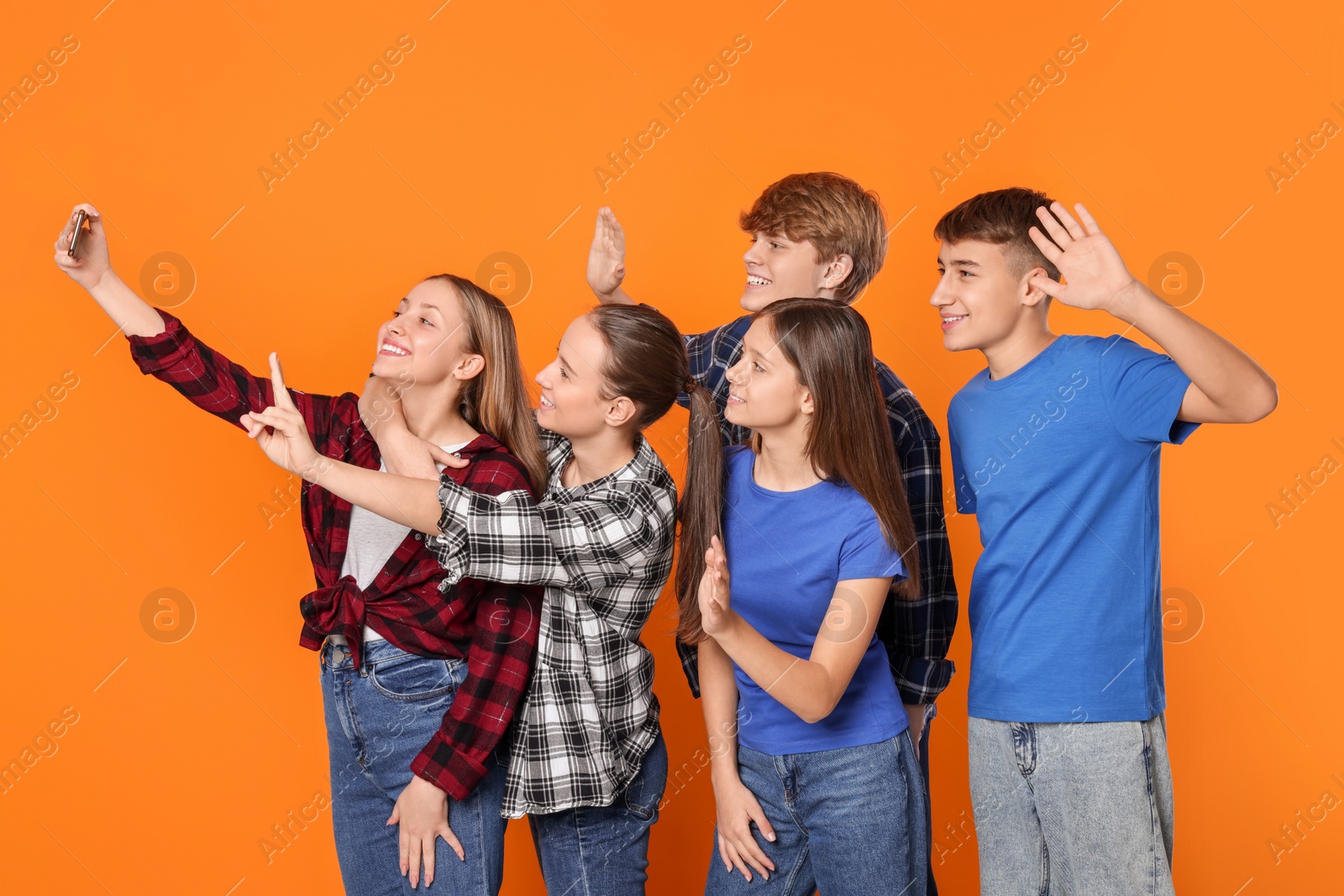 Photo of Group of happy teenagers taking selfie on orange background