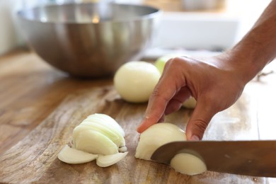 Photo of Woman cutting fresh ripe onion on wooden board, closeup. Space for text