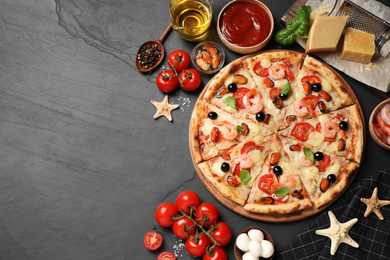 Photo of Tasty pizza with seafood and ingredients on black table, flat lay. Space for text