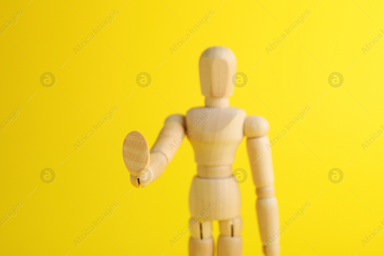 Photo of Wooden human model on yellow background, closeup. Mini mannequin