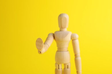 Photo of Wooden human model on yellow background, closeup. Mini mannequin