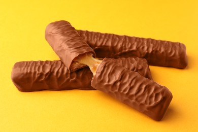 Photo of Sweet tasty chocolate bars with caramel on yellow background