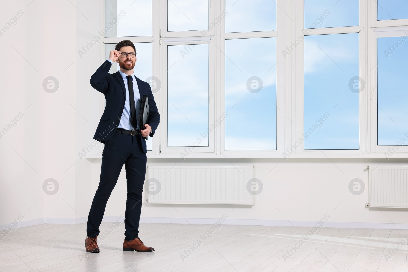 Photo of Handsome real estate agent with documents in empty room, space for text