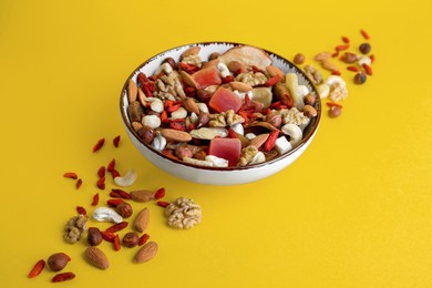 Photo of Bowl with mixed dried fruits and nuts on yellow background