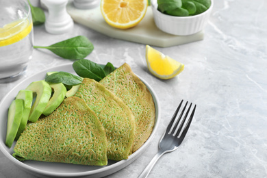 Photo of Delicious spinach crepes with avocado served on marble table