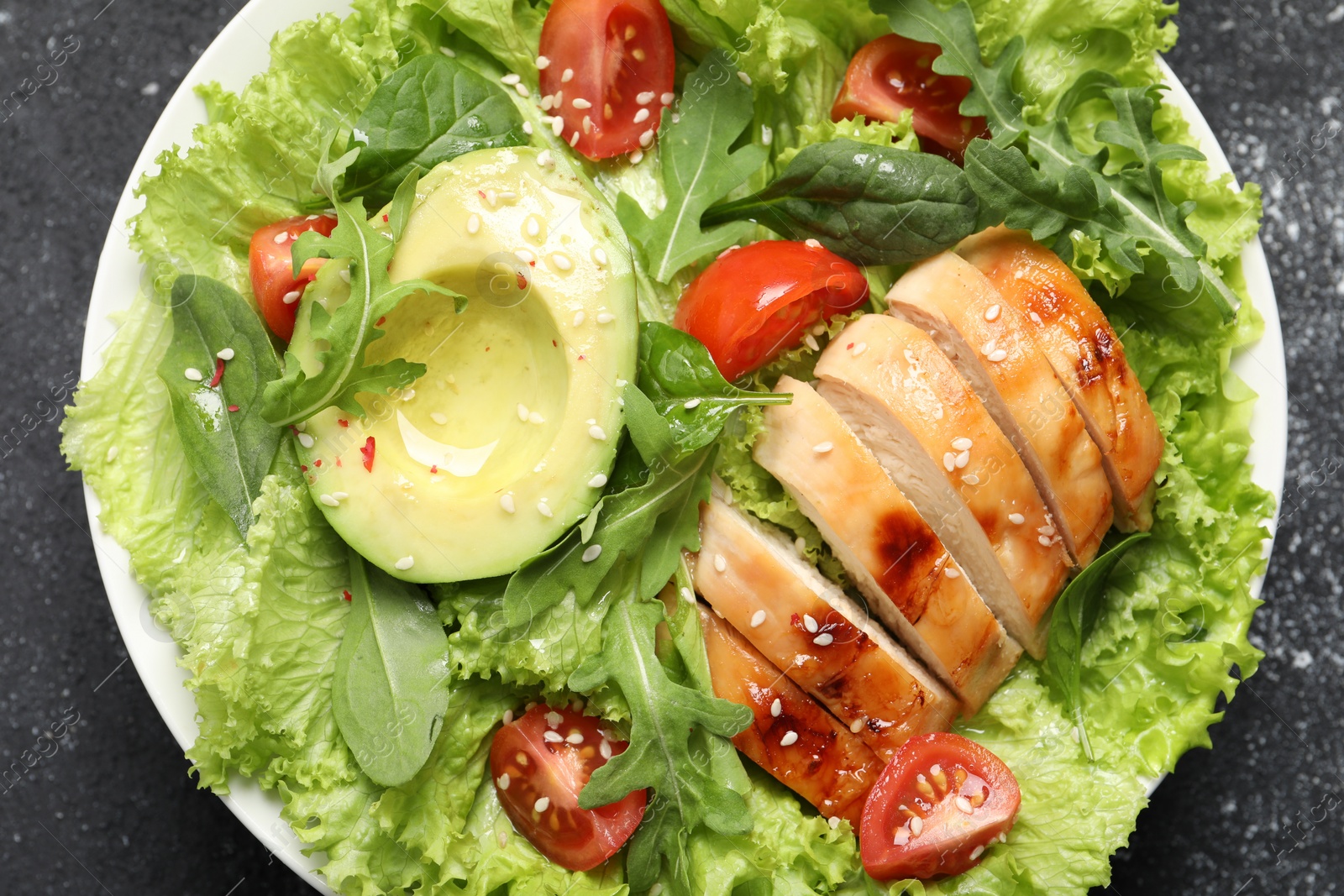 Photo of Delicious salad with chicken, cherry tomato and avocado on grey table, top view