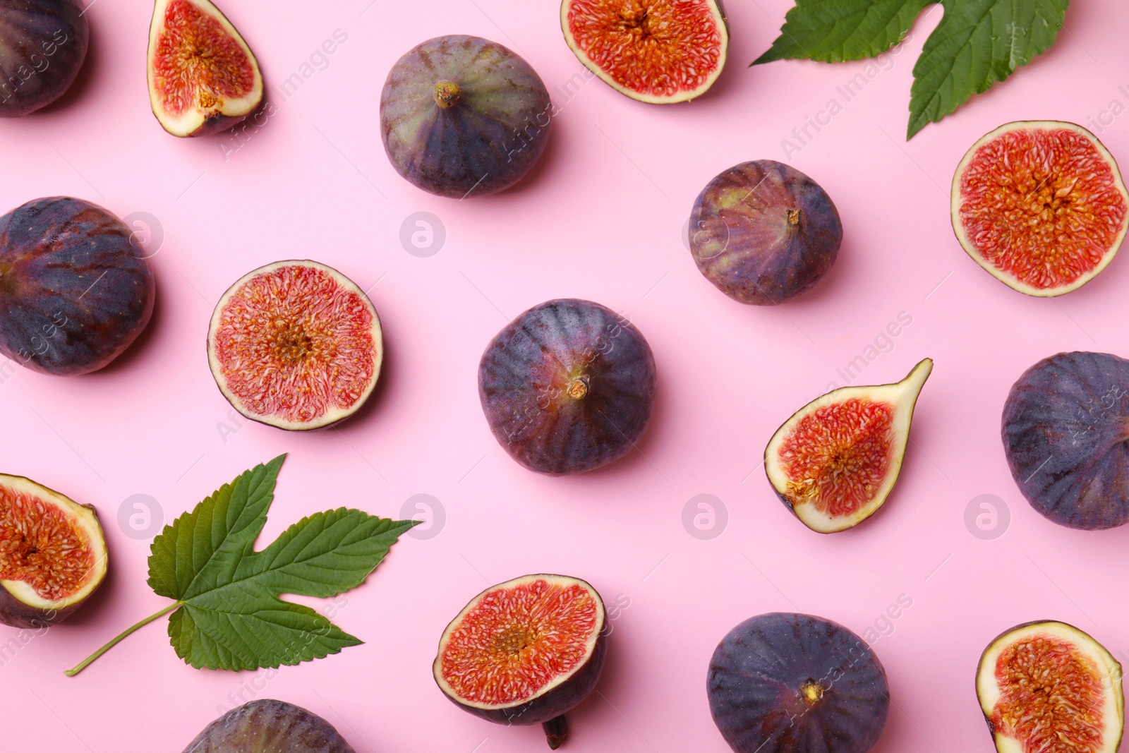 Photo of Fresh ripe figs with green leaves on pink background, flat lay