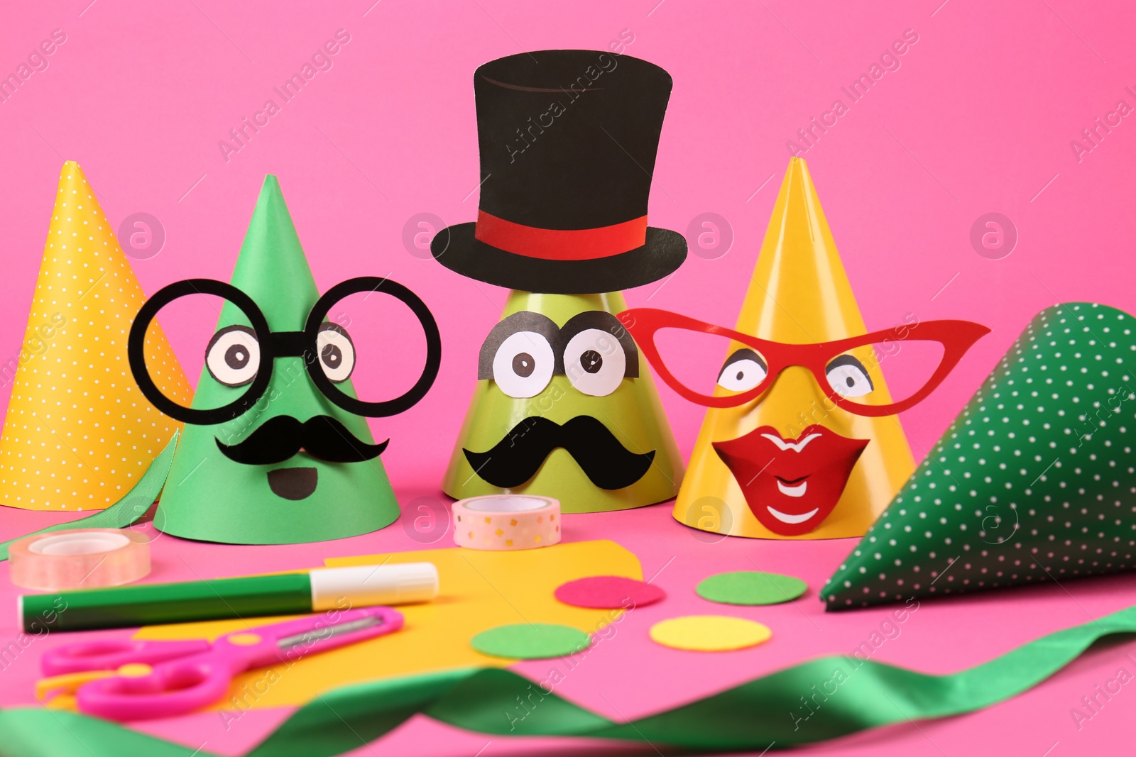 Photo of Funny party hats and different materials on pink background. Handmade decorations