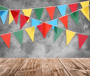 Image of Empty wooden table and decorative bunting flags hanging on grey wall