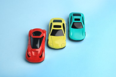 Different bright cars on light blue background, above view. Children`s toys
