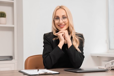 Happy secretary in glasses at table in office