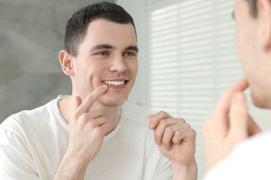 Young smiling man with whitening strips indoors