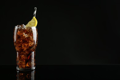 Glass of refreshing soda water with ice cubes and lemon slice on black background, space for text