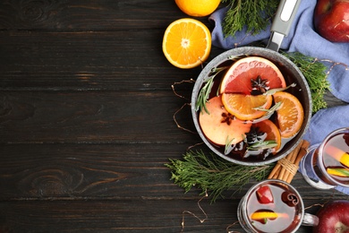 Photo of Tasty mulled wine with spices on wooden table, flat lay. Space for text