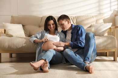 Photo of Young pregnant woman with her husband at home