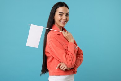 Photo of Happy young woman with blank white flag on light blue background. Mockup for design