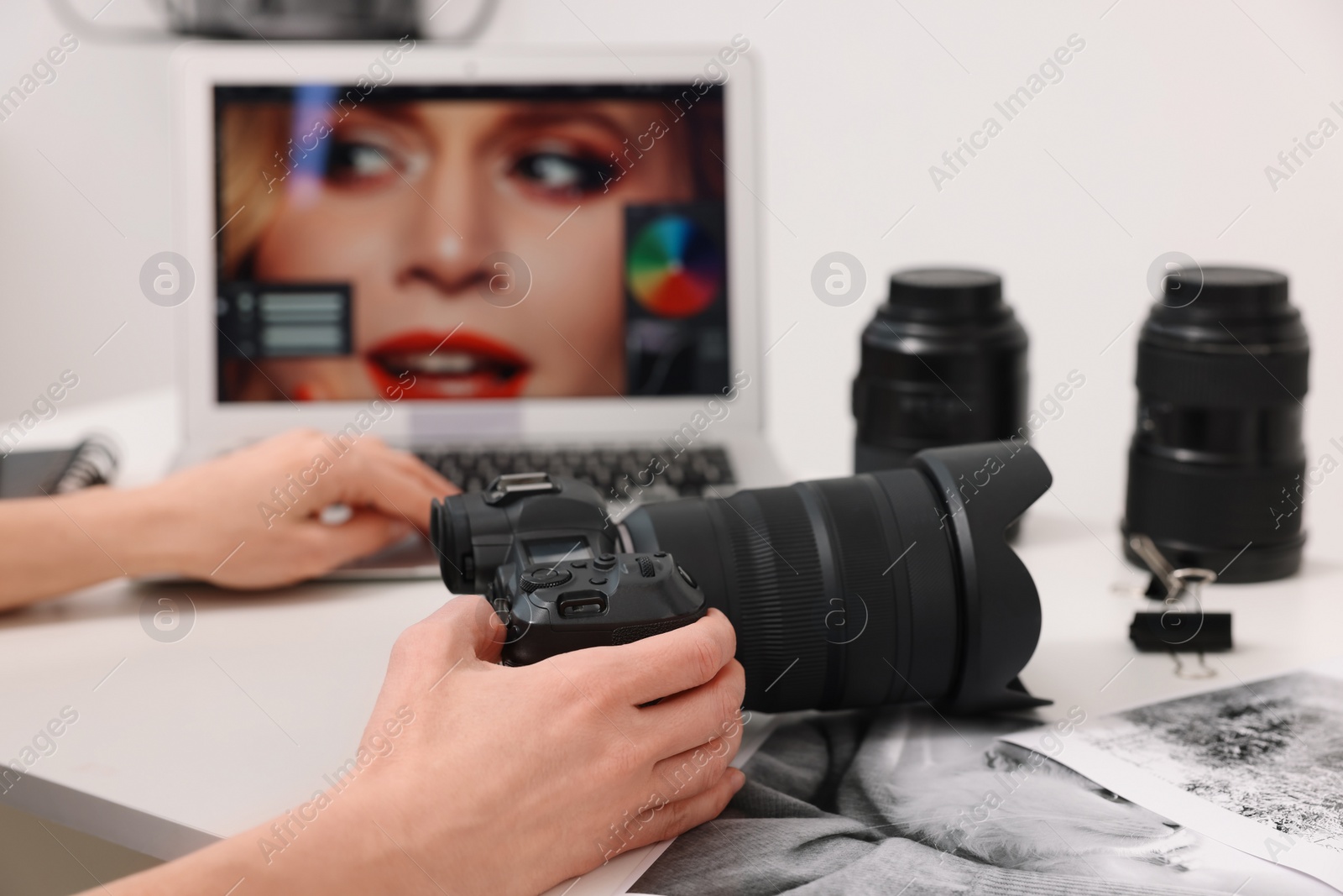 Photo of Professional photographer with digital camera at table indoors, closeup