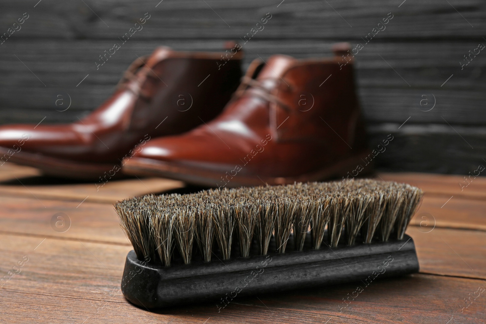 Photo of Shoe brush and leather footwear on wooden surface