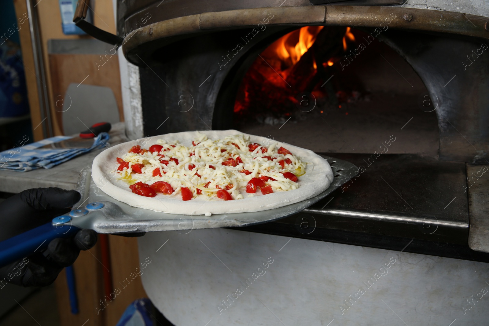 Photo of Chef putting tasty pizza into oven in restaurant kitchen