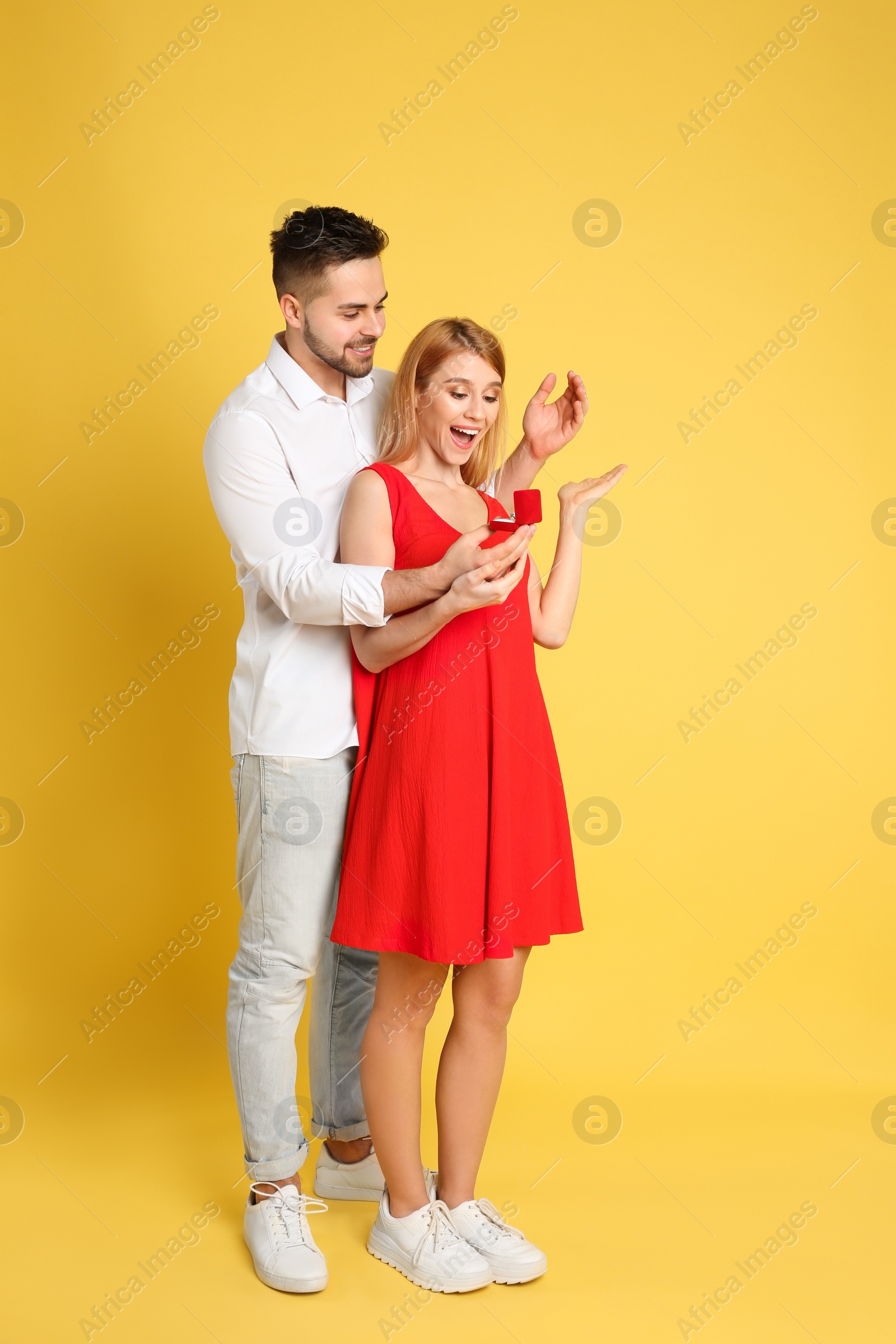 Photo of Man with engagement ring making marriage proposal to girlfriend on yellow background