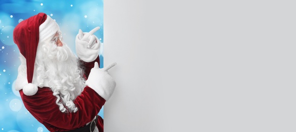 Image of Santa Claus with blank banner on blurred blue background. Space for design