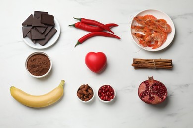 Photo of Natural aphrodisiac. Different food products and red decorative heart on white marble table, flat lay