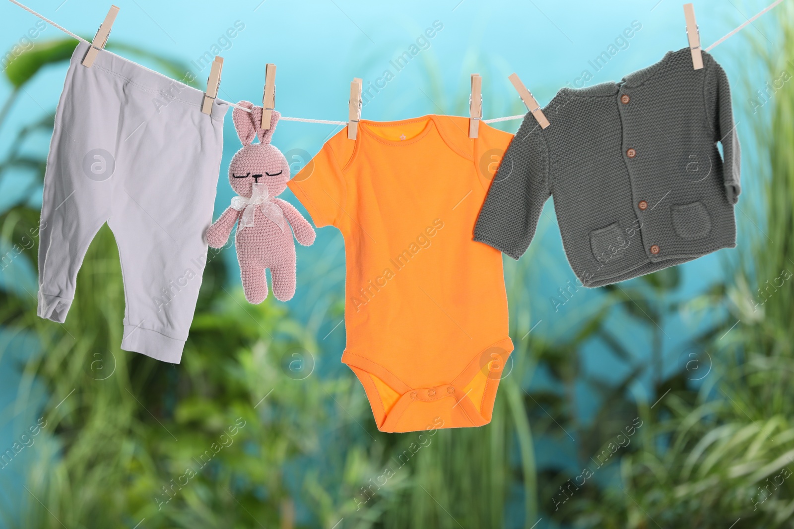 Photo of Baby clothes and bunny toy drying on laundry line outdoors