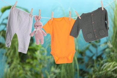 Photo of Baby clothes and bunny toy drying on laundry line outdoors