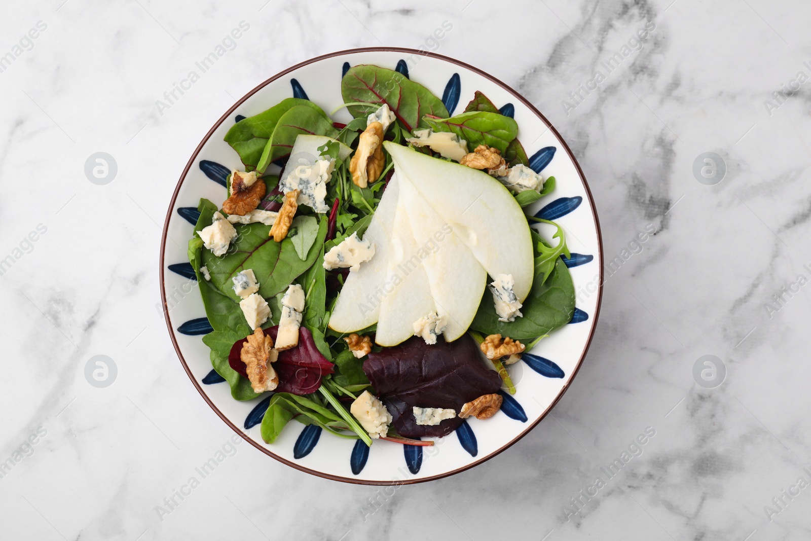 Photo of Delicious pear salad in bowl on white marble table, top view