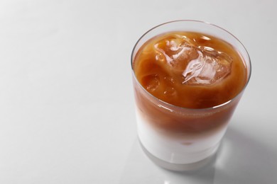 Photo of Glass of iced coffee on white table, closeup. Space for text