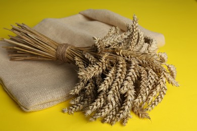 Photo of Bunch of wheat and sack bag on yellow background