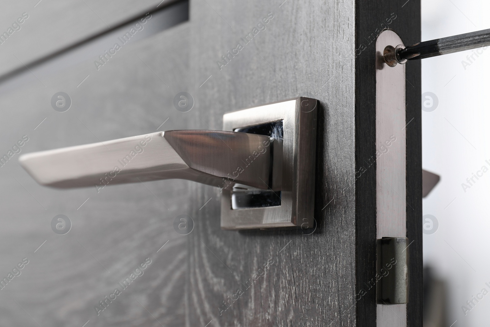 Photo of Repairing door handle with screwdriver indoors, closeup